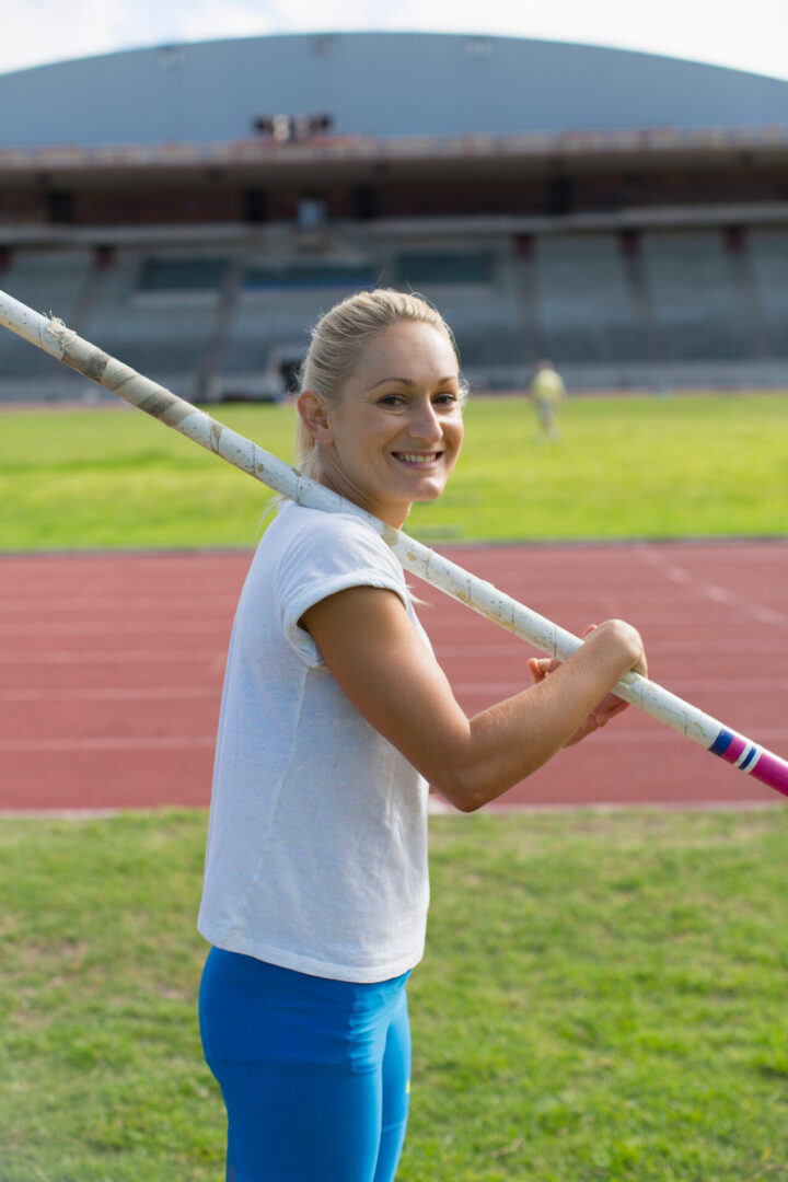 Portrait smiling female track and field athlete practicing pole